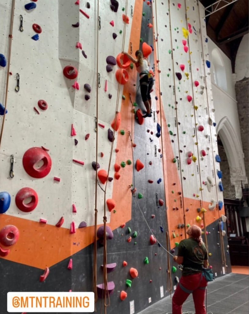 two girls lead climbing in an indoor climbing wall